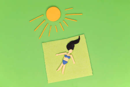 Woman laying in the grass on the blanket under yellow sun. Relax in the greenery, sunbathing, resting in garden concept. Artificial abstract scene, leisure in the green environment during vacations.の写真素材