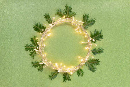 Flat lay top view, Christmas background circle shape border frame, light garland and fir twigs green...