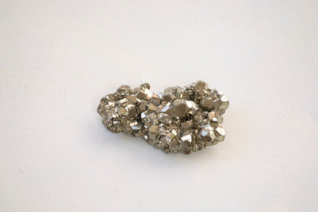 Shiny pyrite stone close-up on white background. Silver colored crystal mineral.の写真素材