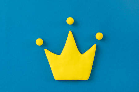 Simple 3d yellow crown symbol on blue background. Concept of win and success, top rank quality status.の写真素材