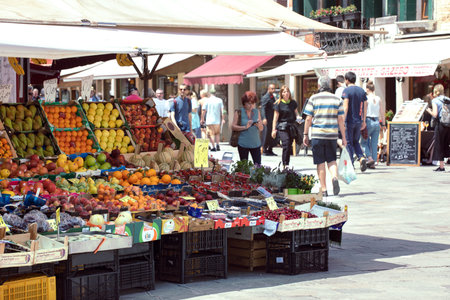 Venice, Italy, 05.26.2022: view on city street with pedestrians and fruits and vegetable market stand on the square.のeditorial素材