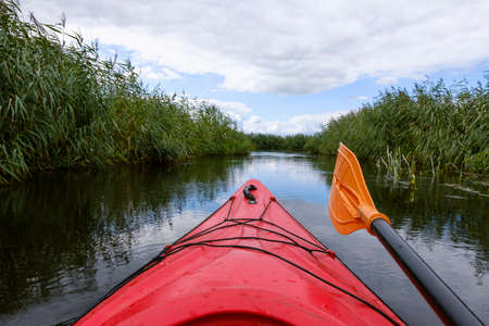 Kayaker point of view. Kayak bow with a view on the river and rushes. River kayaking concept. Active...