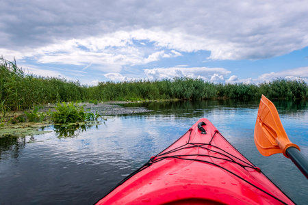 Kayaker point of view with beautiful landscape. Kayak bow with a view on the river and rushes. River kayaking concept. Active holidays in wild nature.の写真素材