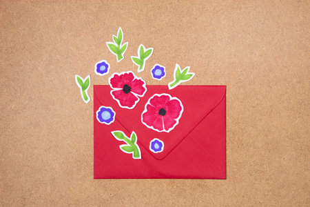 Red envelope with hand drawn flowers deco arrangement on neutral background. Greetings concept, invitation, wedding birthday card.の写真素材