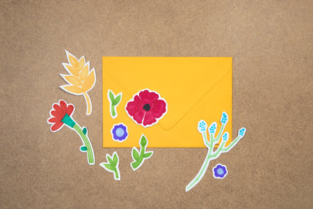 Yellow envelope with hand drawn colorful flowers deco arrangement on neutral background. Letter concept, invitation, wedding birthday card.の写真素材