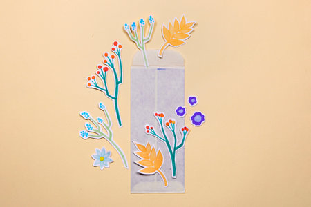 Envelope with paper flowers deco arrangement on neutral background. Greetings concept, invitation, wedding birthday card.の写真素材