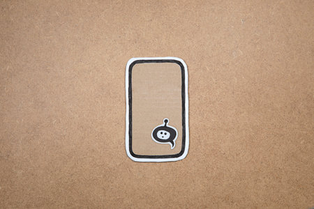Mobile phone made our of paper with bot in the speech bubble on the display, concept of chatting with bot. Asking questions to AI. Cardboard smartphone with bot representation ready to work.の写真素材
