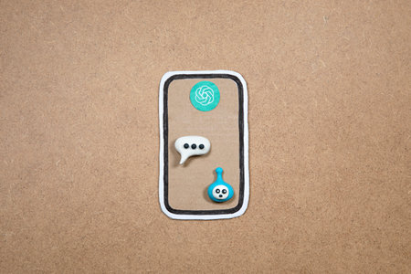 Mobile phone made of paper with bot in the speech bubble on the display, concept of chatting with bot. Asking questions to AI. Cardboard smartphone with bot representation ready to work.の写真素材