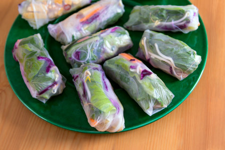 Fresh Spring Rolls on large green plate, view from above. Raw vegan dish, Vietnamese appetizer or main course, colorful vegetables wrapped in rice paper.の写真素材