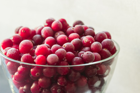 Frozen cranberries in glass bowl closeup on grey background. Selective focus.の写真素材