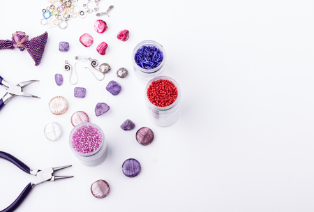 Glass seed and bugle beads, amethyst and turmaline stones, silver toggle, metal beads, shell rose beads, earings, metal rings and pliers for jewelry making and beading  on white background. Top view. Space for text.の写真素材
