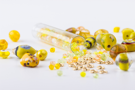 Yellow and lime glass and seed bead mix closeup on white background. Selective focus. Top view.の写真素材