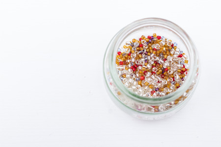 Mix of glass seed beads for jewelry making and beading process on white background. Hobby, handmade, fine arts. Selective focus.の写真素材