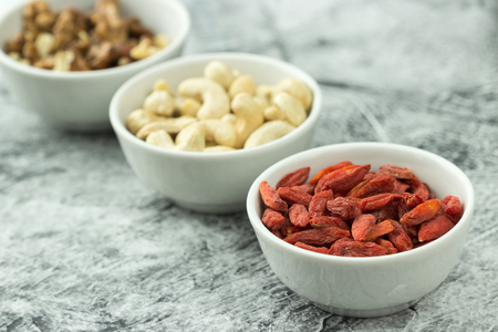 Healthy Breakfast Ingredients in small bowls on table. Walnuts, Cashew, Dry Fruit Goji Berries. Selective Focus.の写真素材