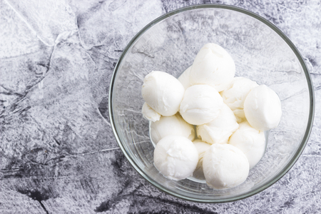 Mozzarella cheese balls in glass bowl on grey background. Selective focus.の写真素材
