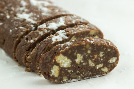 Slices of chocolate italian salami with biscuits and hazelnuts  on white background. Sweet dessert. Selective focus.の写真素材