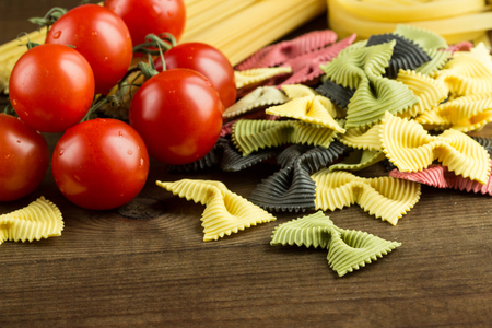 Italian Types of Pasta Farfalle, Spaghetti, with Fresh Tomatoes on Wooden Tableの写真素材