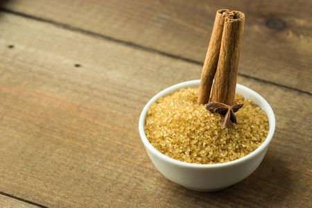 Brown Sugar Bowl with Cinnamon Sticks and Anise Star on Wooden Backgroundの写真素材