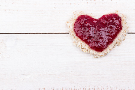 Bread heart sandwich with red raspberries jam for Valentines day on white wooden background. Close-up. Selective focus.の写真素材