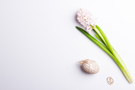 Easter spring background with egg in handmade knitted bag and fresh flower on white background. Space for text. Flat lay.の写真素材