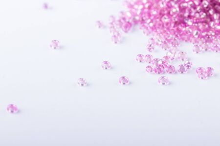 Pink seed beads for beadwork closeup on white background. Selective focus.の写真素材