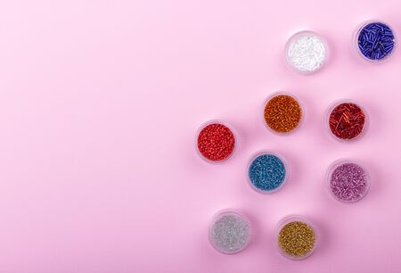 Seed beads in tubes for beading on pink background. Closeup. Hobby, handmade, fine arts. Selective focus. Flat lay.の写真素材