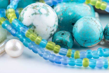 Turquoise gemstones, colorful glass beads, gemstones mix closeup on white background. Selective focus.の写真素材