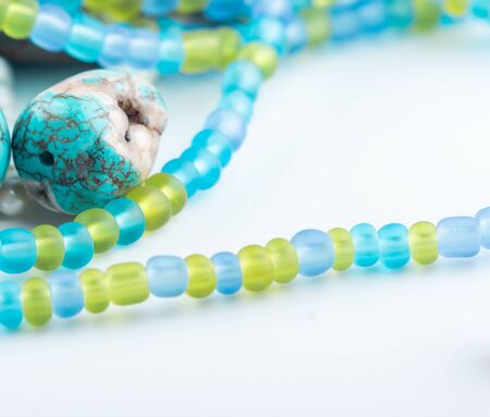 Turquoise gemstones, colorful glass beads, gemstones mix closeup on white background. Selective focus.の写真素材