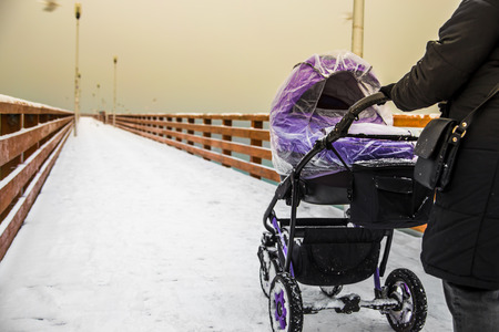 Happy Mother with Baby Stroller Walking near the sea shore and Enjoying winter Sunny Day. Happy...