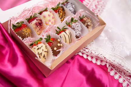 Strawberries in white and milk chocolate on a pink silk backgroundの写真素材