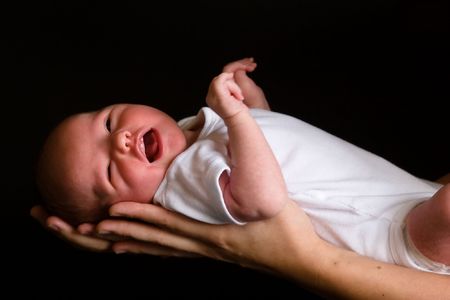 Little 7 days old baby lying securely on mom's arms, against a black backgroundの写真素材