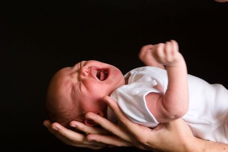 Little 7 days old baby lying securely on mom's arms, against a black backgroundの写真素材