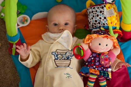 Little caucasian baby girl playing on colorful playmat.
