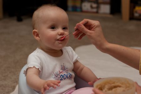 Mother is feeding little caucasian girl with oatmeal cereal.の写真素材