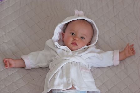 Cute baby girl in white bath robe laying on a floorの写真素材