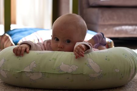Caucasian baby girl playing on her colorful playmat.