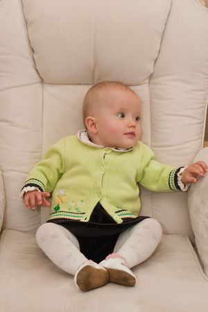 Cute caucasian little baby girl sitting o a chair.