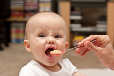 Mother is feeding little caucasian girl with oatmeal cereal.の写真素材