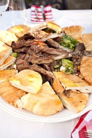 Grilled lamb ribs with pita bread and vegetables.の写真素材