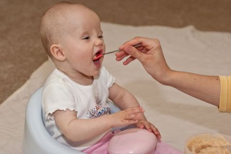 Mother is feeding little caucasian girl with oatmeal cereal.の写真素材