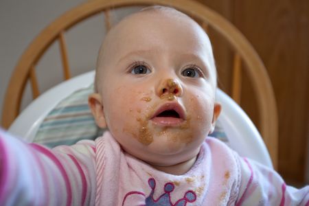 Cute little caucasian girl with oatmeal all over her face.の写真素材