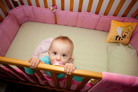 Cute Caucasian baby girl playing in her crib during a day.の写真素材