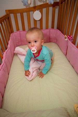 Cute Caucasian baby girl playing in her crib during a day.の写真素材