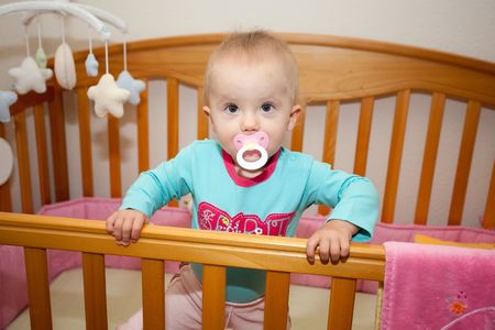 Cute Caucasian baby girl playing in her crib during a day.の写真素材