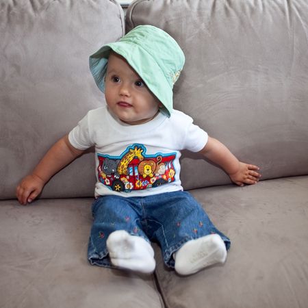 Little caucasian baby girl sitting on a sofa.の写真素材