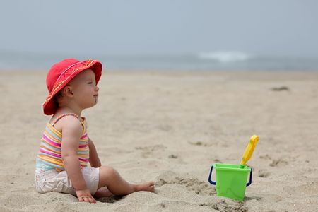 Cute Caucasian baby girl playing with the sand on the beach.の写真素材