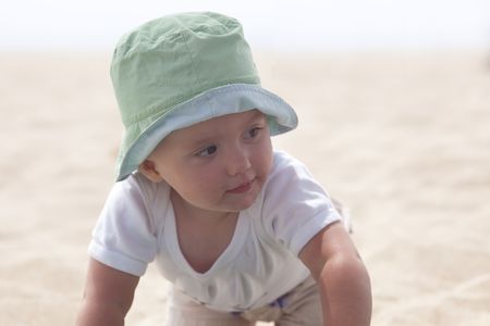 Cute Caucasian baby girl playing with the sand on the beach.の写真素材