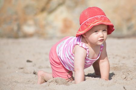 Cute Caucasian baby girl playing with the sand on the beach.の写真素材