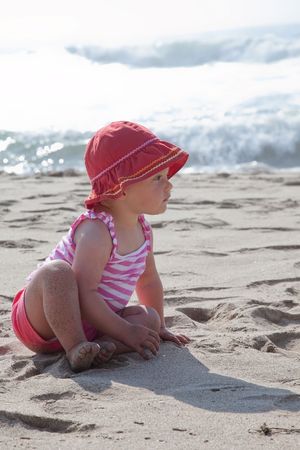 Cute Caucasian baby girl playing with the sand on the beach.の写真素材