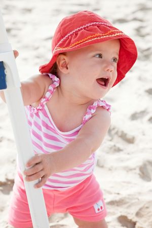 Cute Caucasian baby girl playing with the sand on the beach.の写真素材
